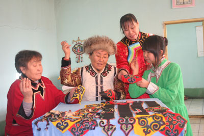 ６４岁的猎民妇女何英莲（左二）在传授外孙女刺绣技艺